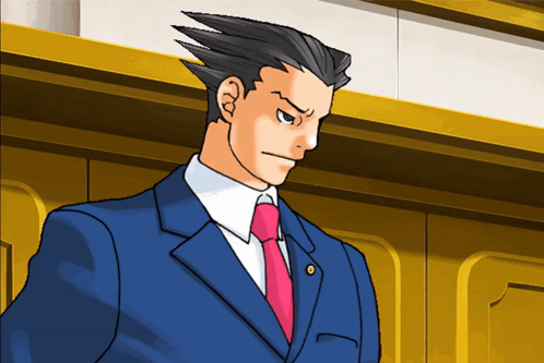 A Man In A Suit And Tie Stands In Front Of A Gold Wall GIF