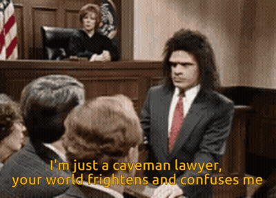 A Man In A Suit And Tie Stands In Front Of A Group Of People And Says I 'M Just A Caveman GIF