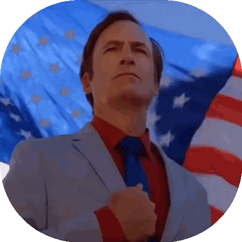 A Man In A Suit And Tie Stands In Front Of A Large American Flag Sticker
