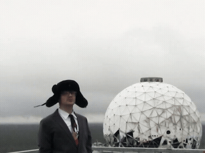 A Man In A Suit And Tie Stands In Front Of A Large White Dome GIF