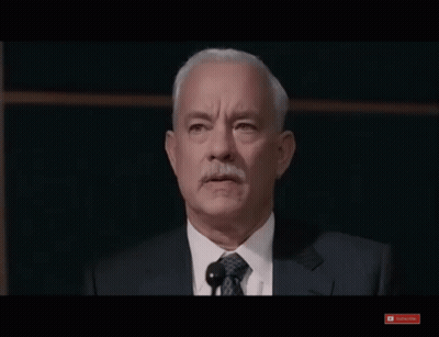 A Man In A Suit And Tie Stands In Front Of A Microphone And A Youtube Subscribe Button GIF