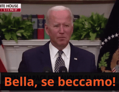 A Man In A Suit And Tie Stands In Front Of A Microphone With The Words Bella Se Beccamo On The Bottom GIF