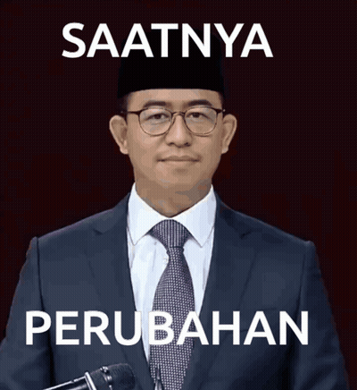 A Man In A Suit And Tie Stands In Front Of A Microphone With The Words Saatnya Perubahan Written Below Him GIF