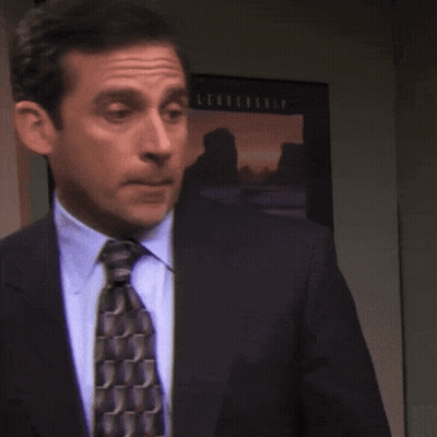A Man In A Suit And Tie Stands In Front Of A Picture That Says ' Sunset ' On It GIF