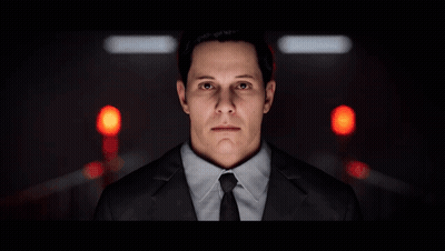 A Man In A Suit And Tie Stands In Front Of A Red Light GIF
