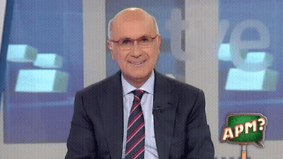 A Man In A Suit And Tie Stands In Front Of A Sign That Says Apm On It GIF