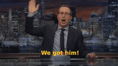 A Man In A Suit And Tie Stands In Front Of A Sign That Says We Come GIF
