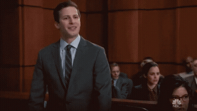 A Man In A Suit And Tie Stands In Front Of A Wall That Says Cool On It GIF