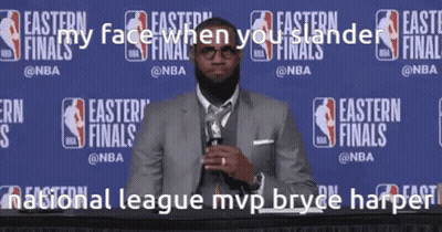 A Man In A Suit And Tie Stands In Front Of A Wall That Says Easter Finals GIF