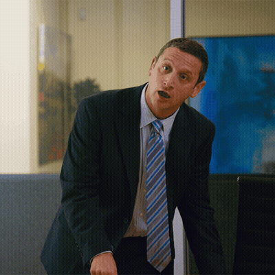 A Man In A Suit And Tie Stands In Front Of A Window GIF