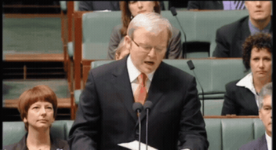 A Man In A Suit And Tie Stands In Front Of Two Microphones GIF