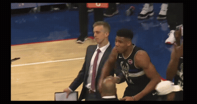 A Man In A Suit And Tie Stands Next To A Basketball Player Wearing A Jersey With The Letter A On It GIF