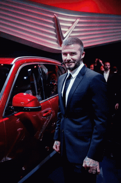A Man In A Suit And Tie Stands Next To A Red Car GIF
