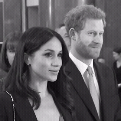 A Man In A Suit And Tie Stands Next To A Woman GIF