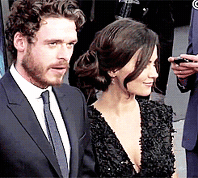 A Man In A Suit And Tie Stands Next To A Woman In A Dress GIF