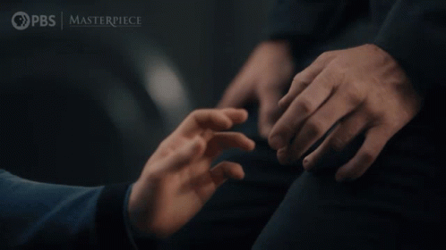 A Man In A Suit And Tie Stands Next To A Woman In A Room With The Words Pbs Masterpiece On The Bottom Right GIF