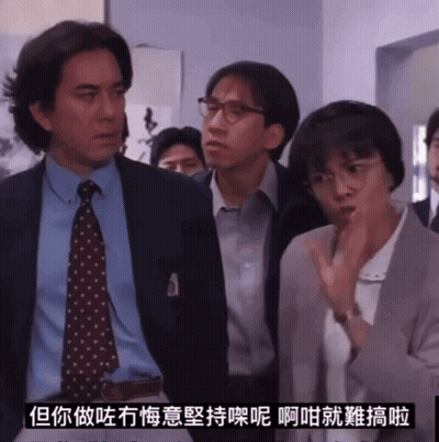A Man In A Suit And Tie Stands Next To A Woman In Glasses GIF