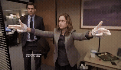 A Man In A Suit And Tie Stands Next To A Woman Wearing Gloves GIF