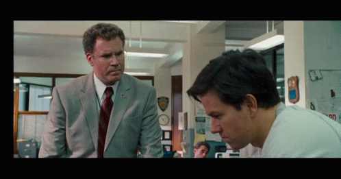 A Man In A Suit And Tie Stands Next To Another Man GIF