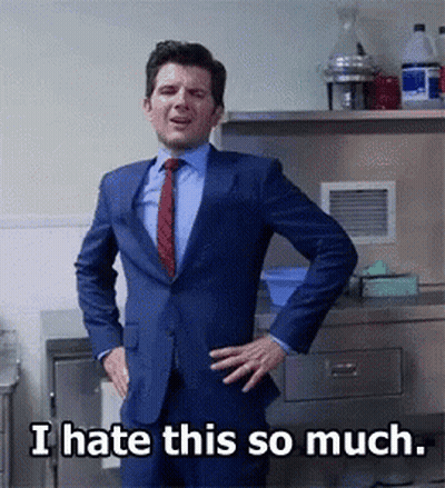 A Man In A Suit And Tie Stands With His Hands On His Hips And Says " I Hate This So Much " GIF