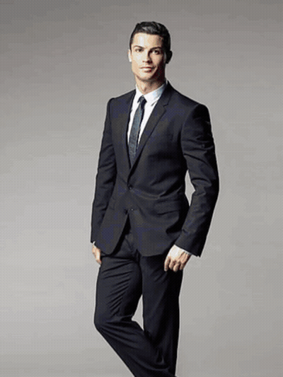 A Man In A Suit And Tie Stands With His Leg Crossed GIF