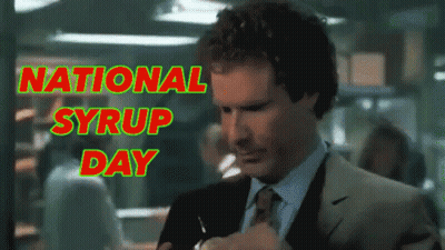 A Man In A Suit And Tie Takes A Sip Of Syrup In Front Of A Sign That Says National Syrup Day GIF