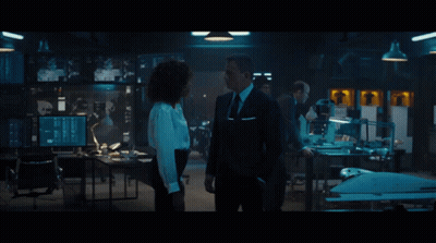 A Man In A Suit And Tie Talks To A Woman In A White Shirt GIF