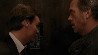 A Man In A Suit And Tie Talks To Another Man In A Black Jacket GIF