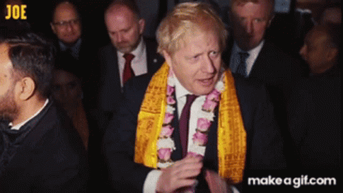 A Man In A Suit And Tie Wearing A Yellow Scarf Around His Neck GIF