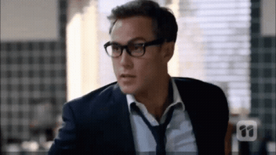A Man In A Suit And Tie Wearing Glasses And A Tie . GIF