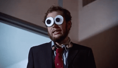 A Man In A Suit And Tie Wearing Googly Eyes GIF
