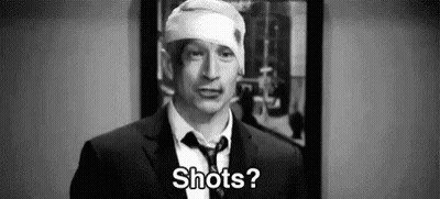 A Man In A Suit And Tie With A Bandage On His Head Is Asking Shots . GIF