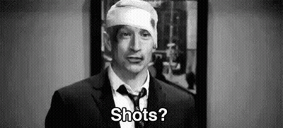 A Man In A Suit And Tie With A Bandage On His Head Is Asking Shots . GIF