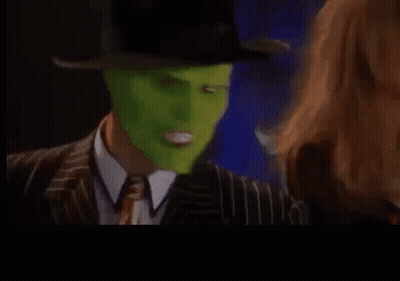 A Man In A Suit And Tie With A Green Mask On His Face Is Making A Funny Face . GIF