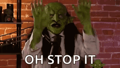 A Man In A Suit And Tie With A Green Mask On His Face Is Making A Stop Sign . GIF