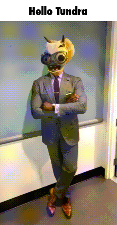 A Man In A Suit And Tie With A Mask On His Head Is Standing In A Hallway With The Words Hello Tundra Above Him GIF