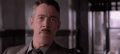A Man In A Suit And Tie With A Mustache Is Making A Funny Face . GIF