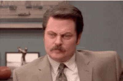 A Man In A Suit And Tie With A Mustache Is Sitting At A Desk . GIF