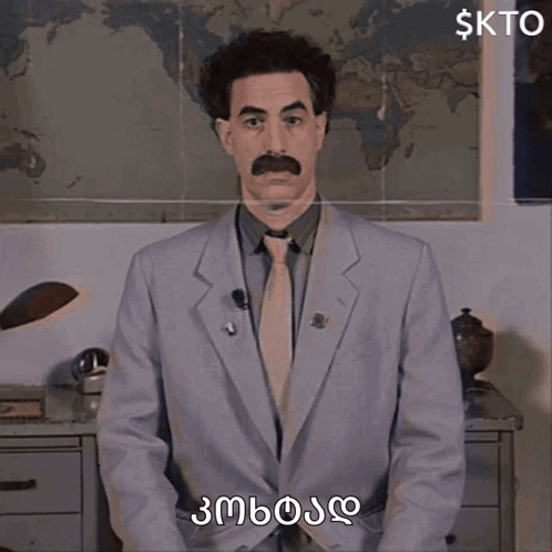 A Man In A Suit And Tie With A Mustache Is Standing In Front Of A Map Of The World And Says Kto GIF