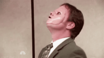 A Man In A Suit And Tie With A Red Face Painted On His Face . GIF