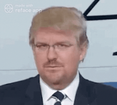 A Man In A Suit And Tie With Glasses And A Beard Is Making A Funny Face . GIF