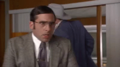 A Man In A Suit And Tie With Glasses And A Clip On His Tie GIF