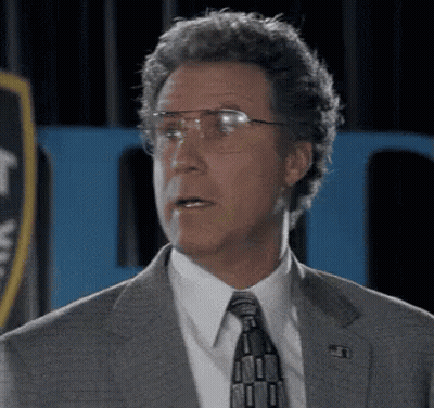 A Man In A Suit And Tie With Glasses Is Making A Funny Face . GIF