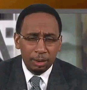 A Man In A Suit And Tie With Glasses Is Making A Funny Face . GIF
