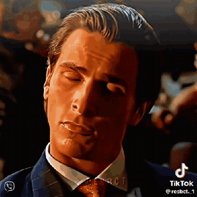 A Man In A Suit And Tie With His Eyes Closed And A Cigarette In His Mouth . GIF