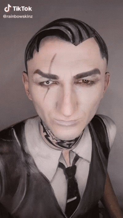 A Man In A Suit And Tie With His Face Painted . GIF