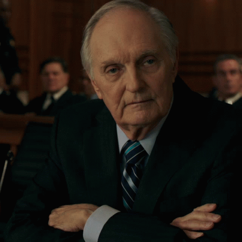 A Man In A Suit And Tie With His Hands Folded GIF