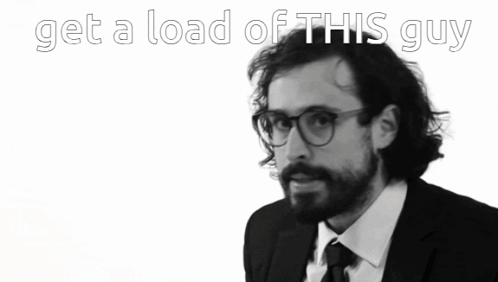 A Man In A Suit And Tie With The Words Get A Load Of This Guy Behind Him GIF