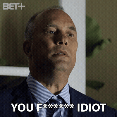 A Man In A Suit And Tie With The Words You F *** Idiot Above Him GIF
