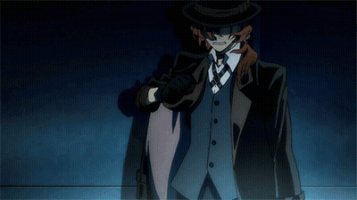 A Man In A Suit And Top Hat Is Standing In A Dark Room GIF